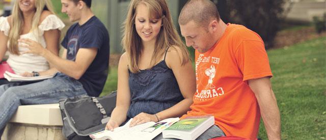 Carroll University students sitting reading a book together.